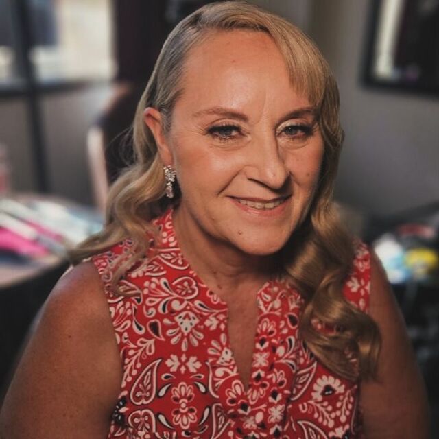 A woman in a red paisley shirt is smiling for the camera