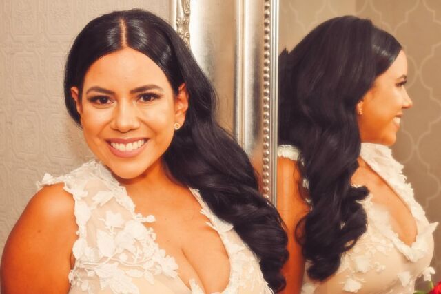 A woman in a white dress is smiling in front of a mirror.