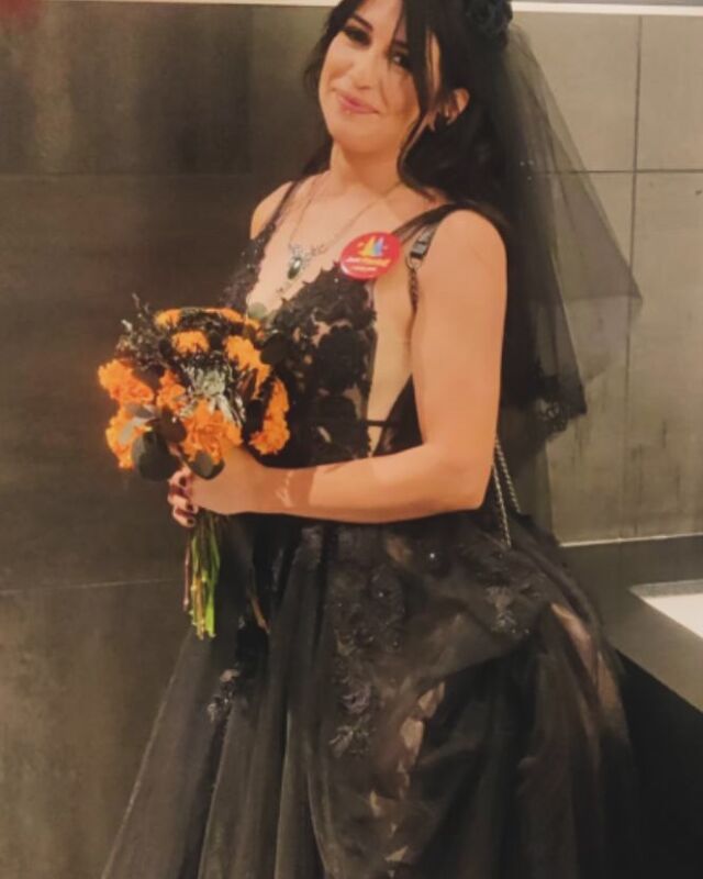 A woman in a black dress is holding a bouquet of flowers.