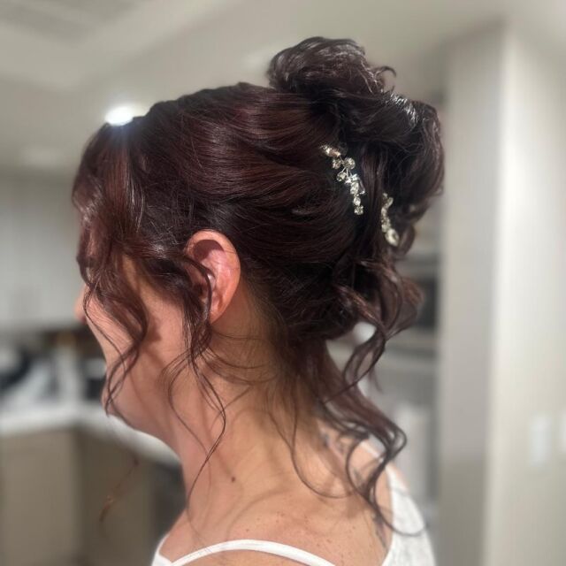 A woman has her hair in a bun with rhinestones in it