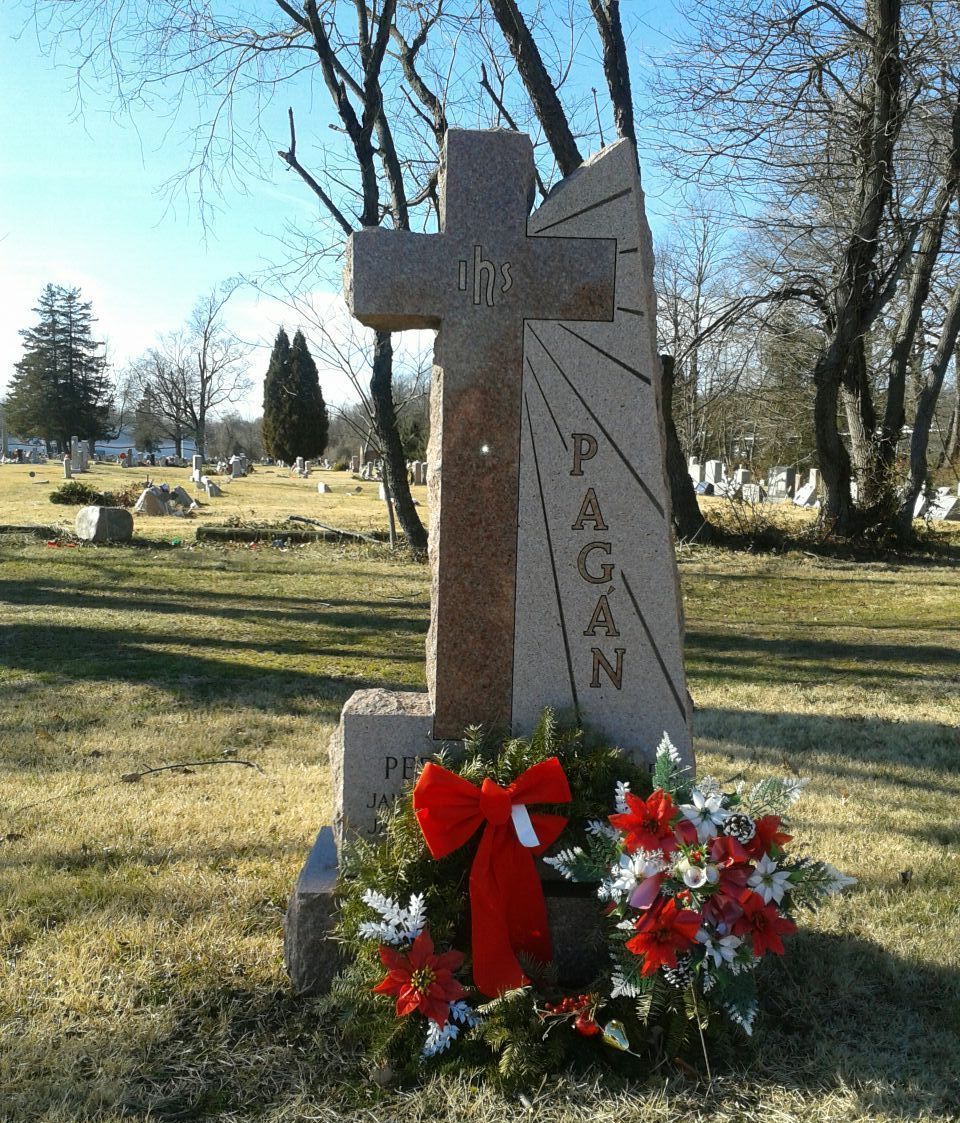 A light brown stone tombstone featuring a cross and the name 