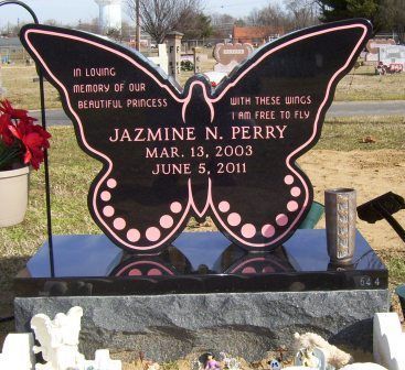 A black butterfly-shaped granite headstone with pink lettering and trim, memorializing Jazmine N. Perry in a cemetery.