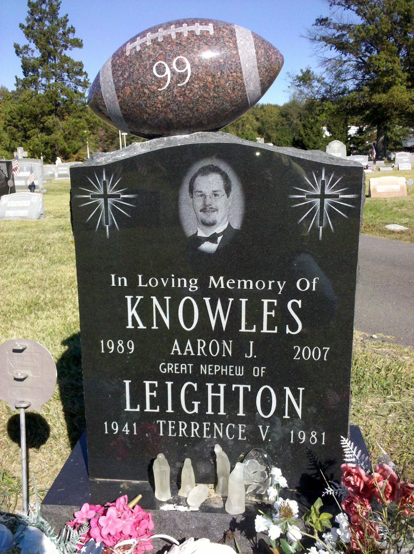 A black granite headstone with a football topper marked 