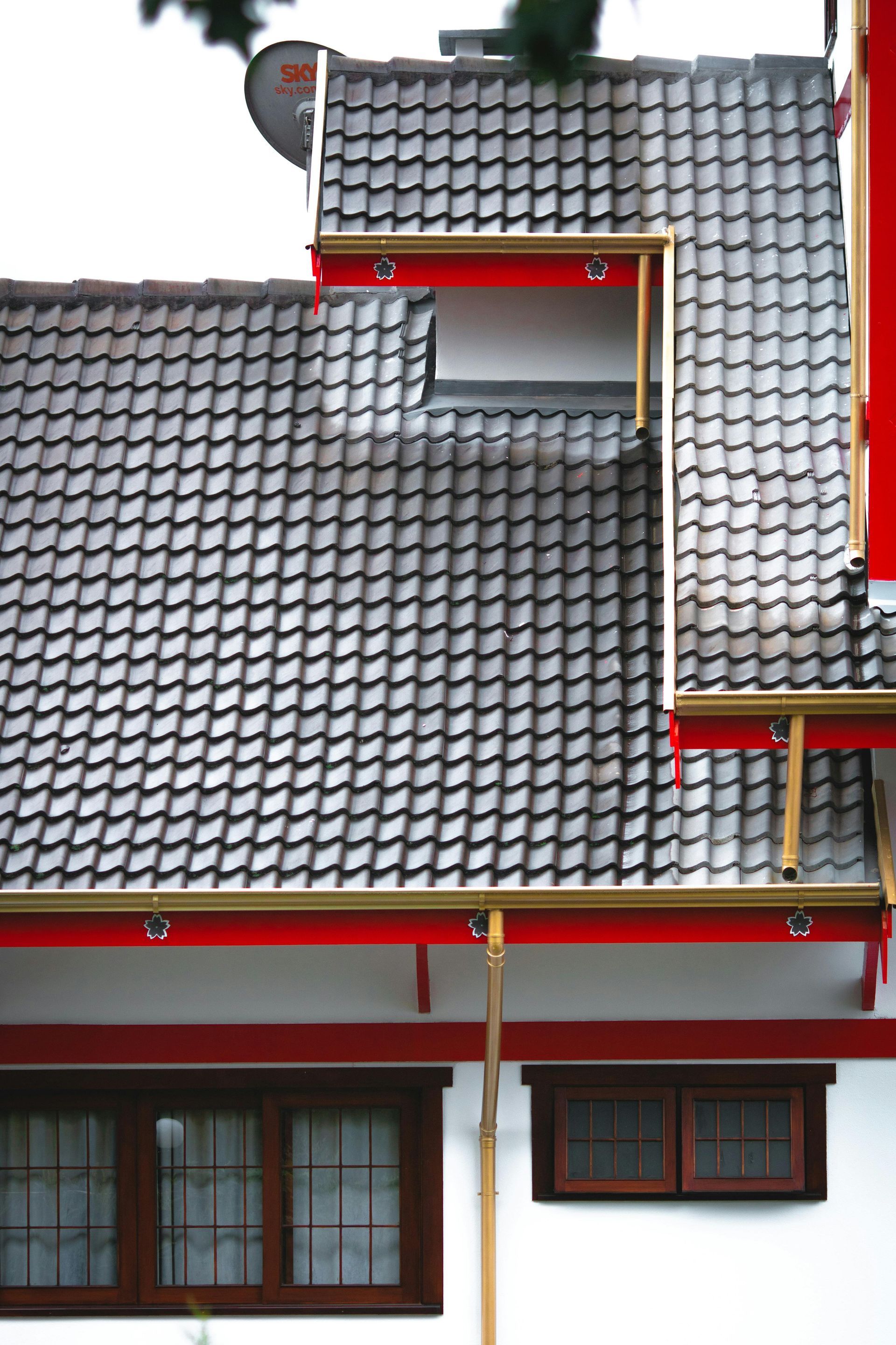 A house with a gray tiled roof and red trim