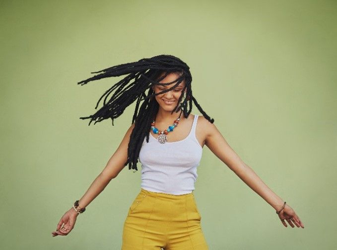 Black woman smiling and playing with her braids, showcasing beautiful hair braids style