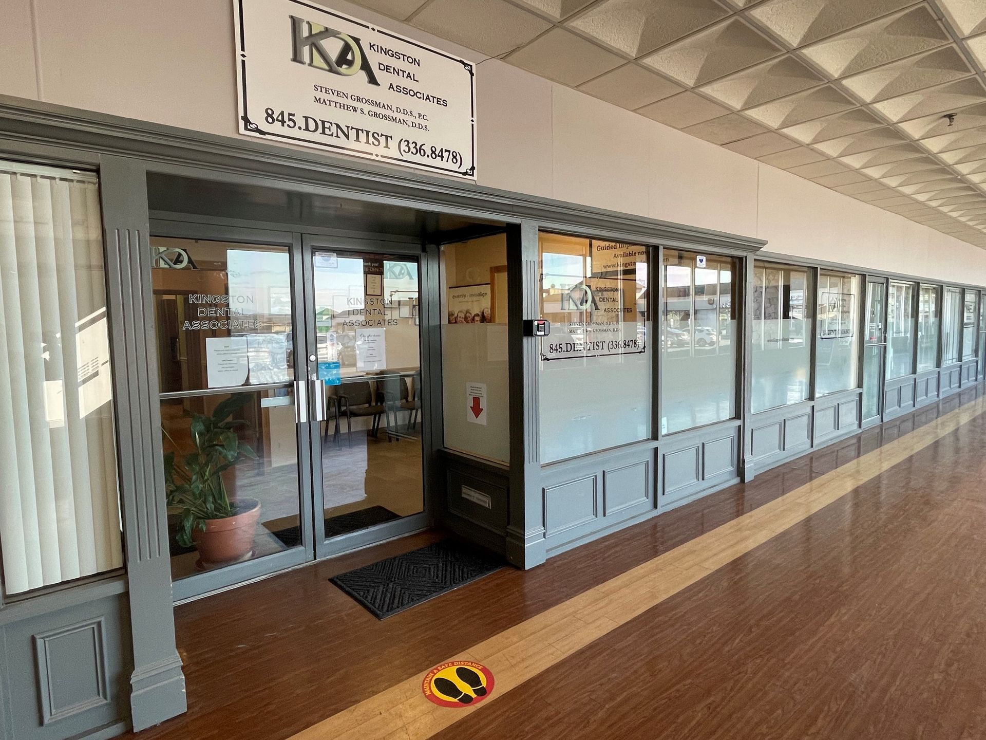 Entrance to an office with glass doors and windows. Sign above reads 