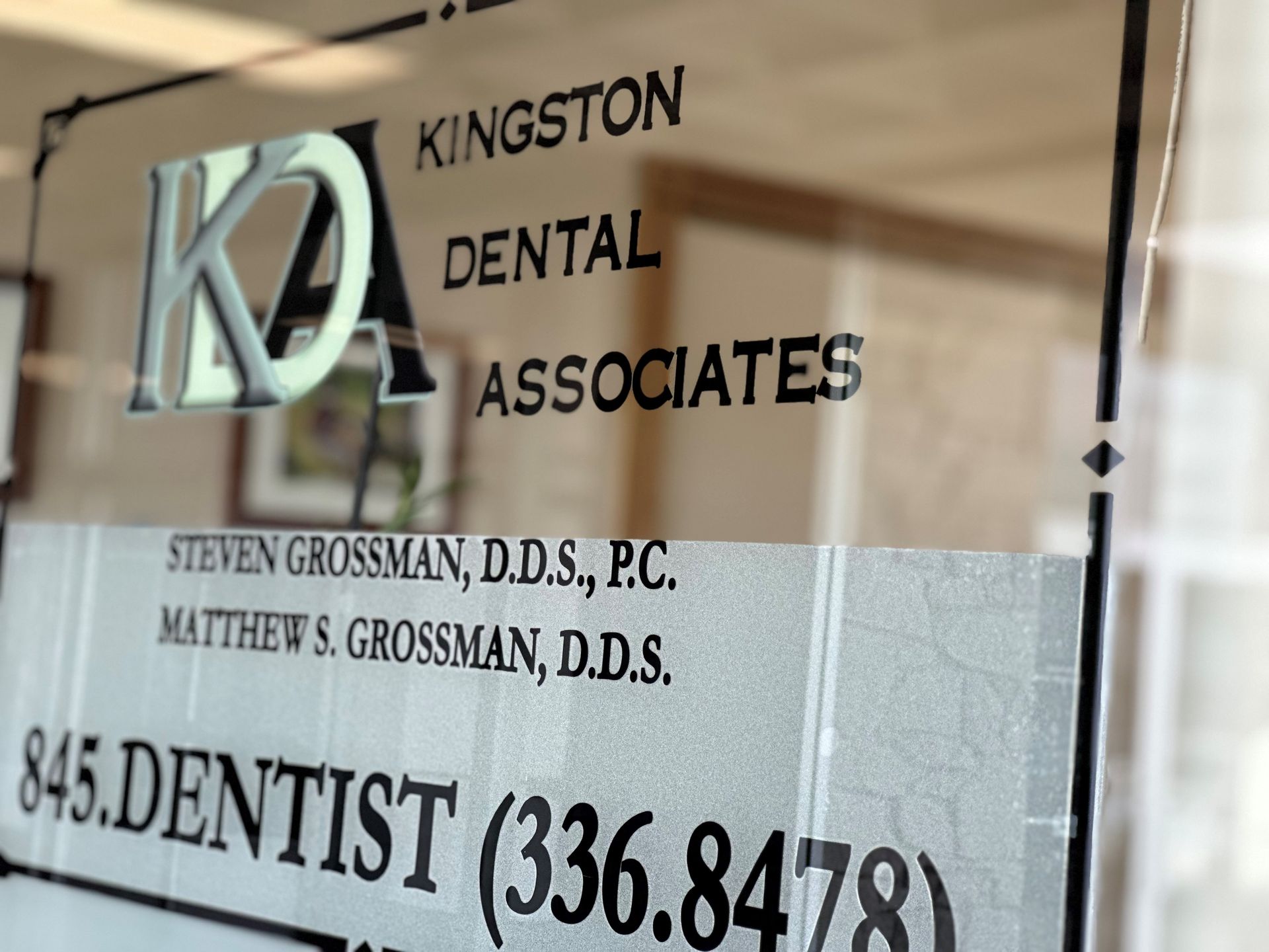 Sign for Kingston Dental Associates: text on glass with names and phone number.