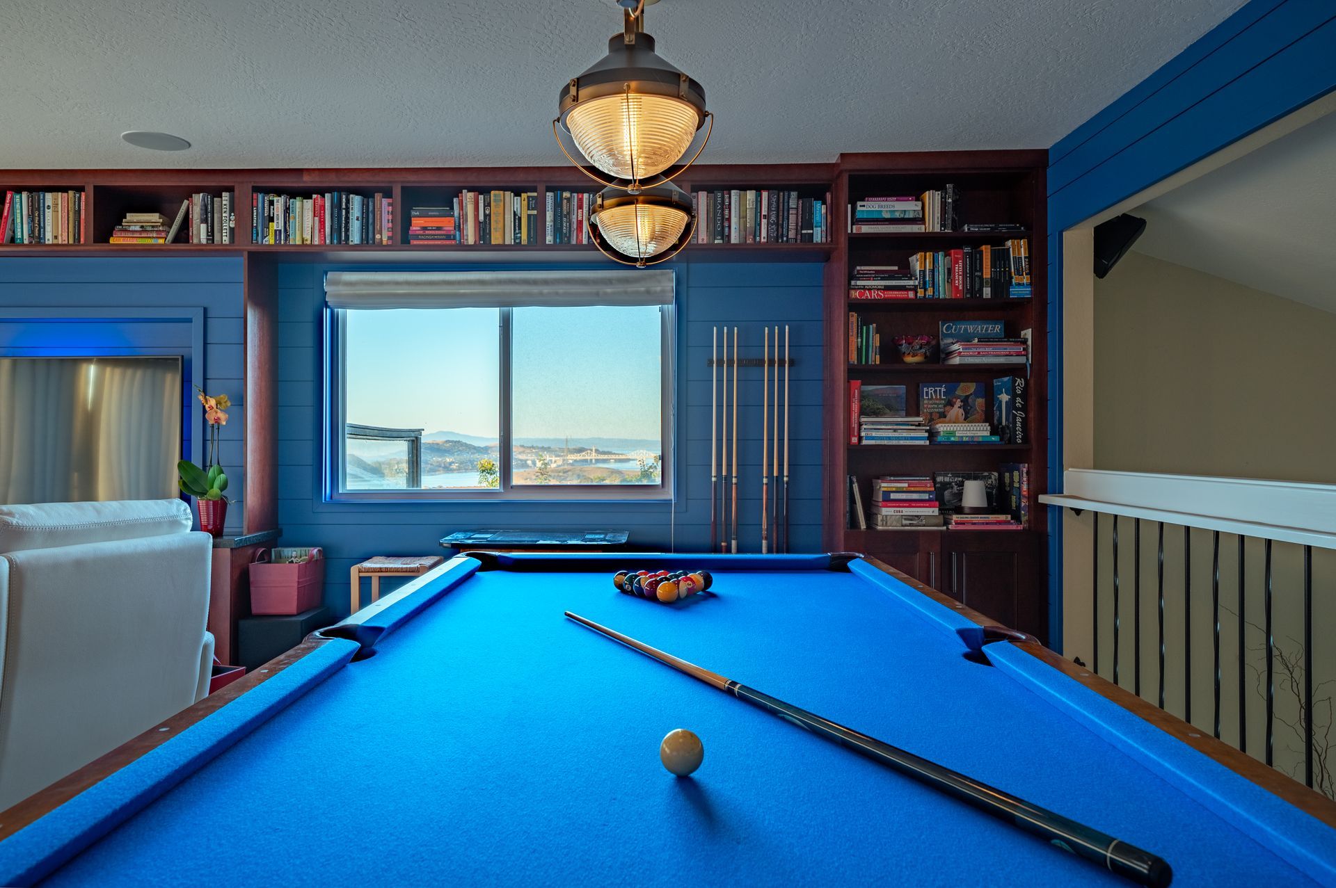 a pool table in a living room with bookshelves behind it