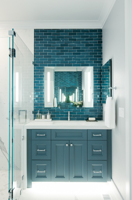 A bathroom with blue cabinets and a brick wall