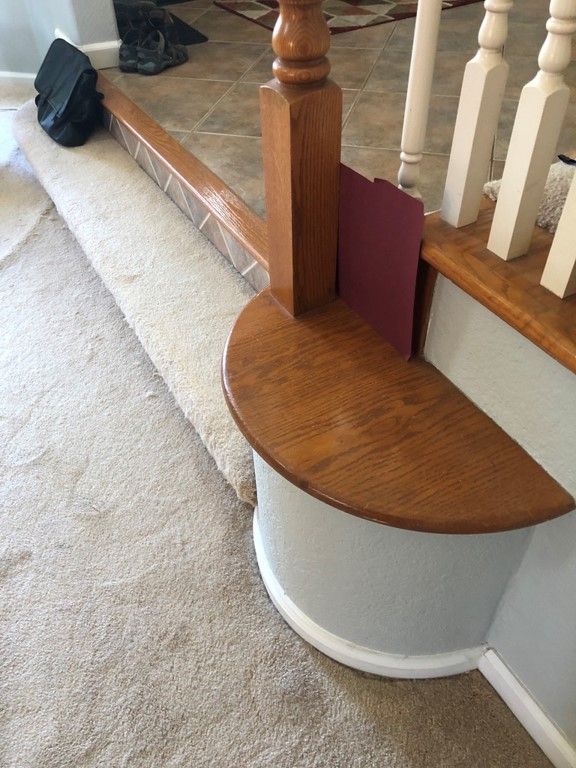 A staircase with a wooden railing and a carpeted floor