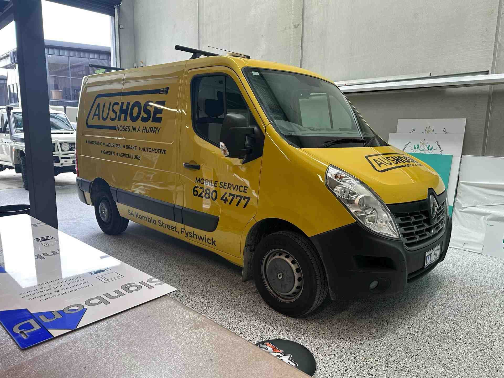 A Yellow Van With the Word Aushose on the Side is Parked in a Garage — Aushose Canberra In Fyshwick, ACT