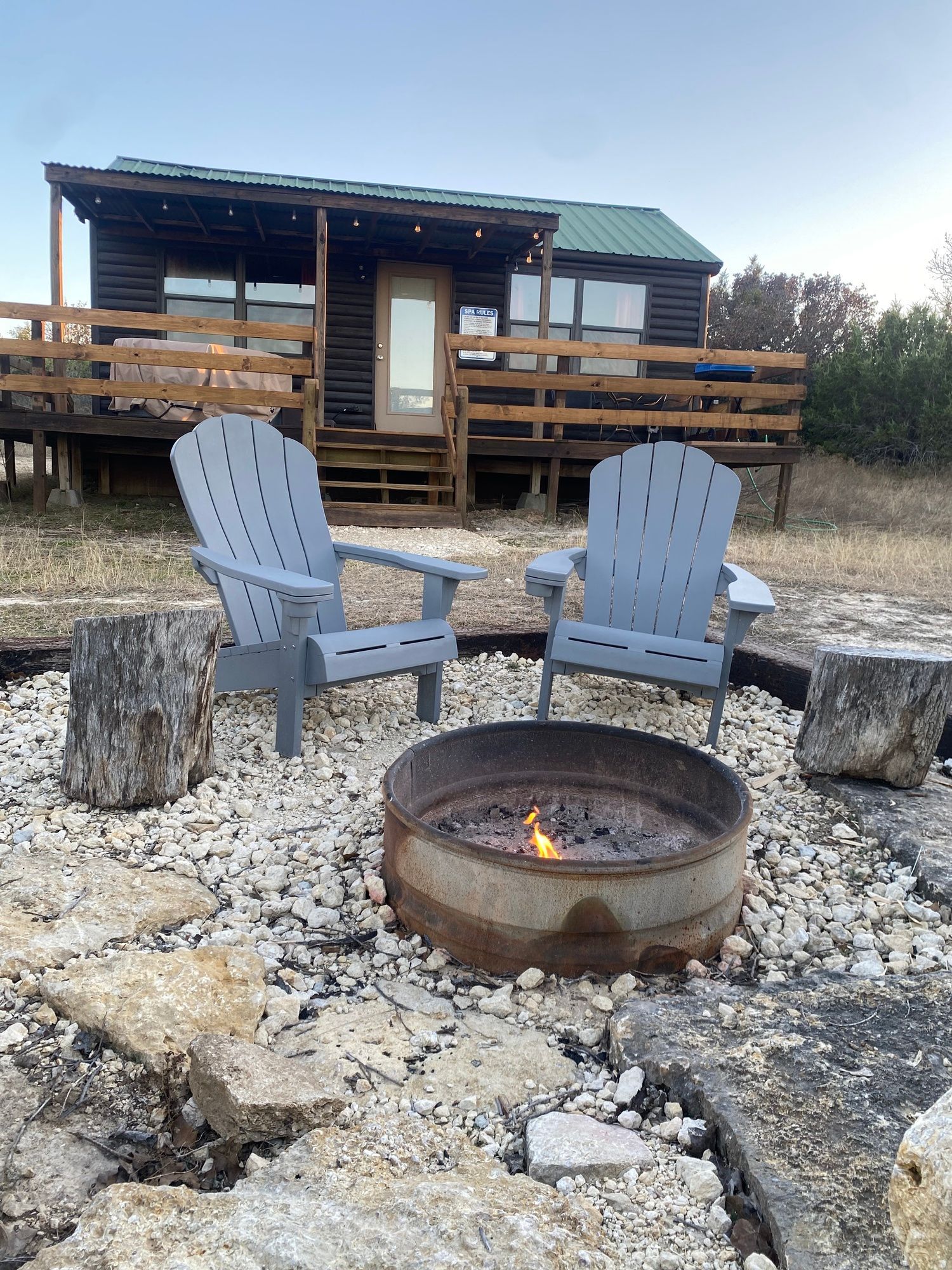 Two chairs are sitting next to a fire pit in front of a cabin.