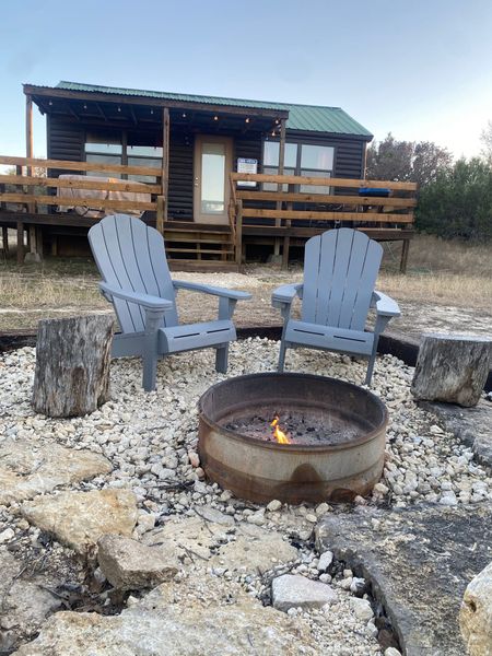 Two chairs are sitting next to a fire pit in front of a cabin.
