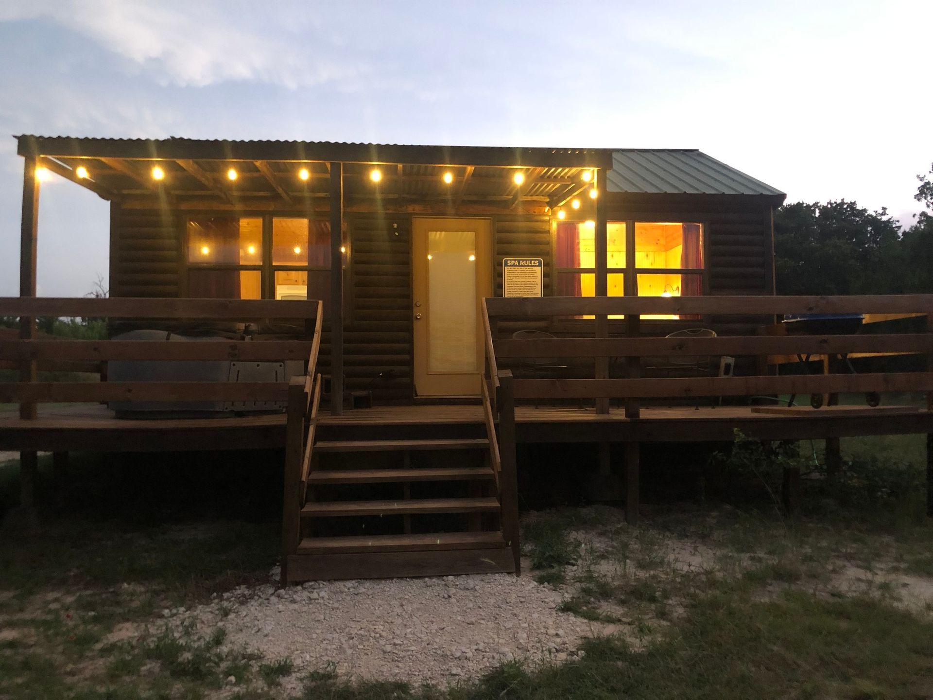 A small house with a porch and stairs is lit up at night.