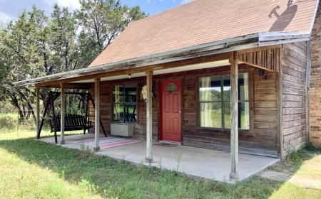 A small wooden house with a porch and a red door.