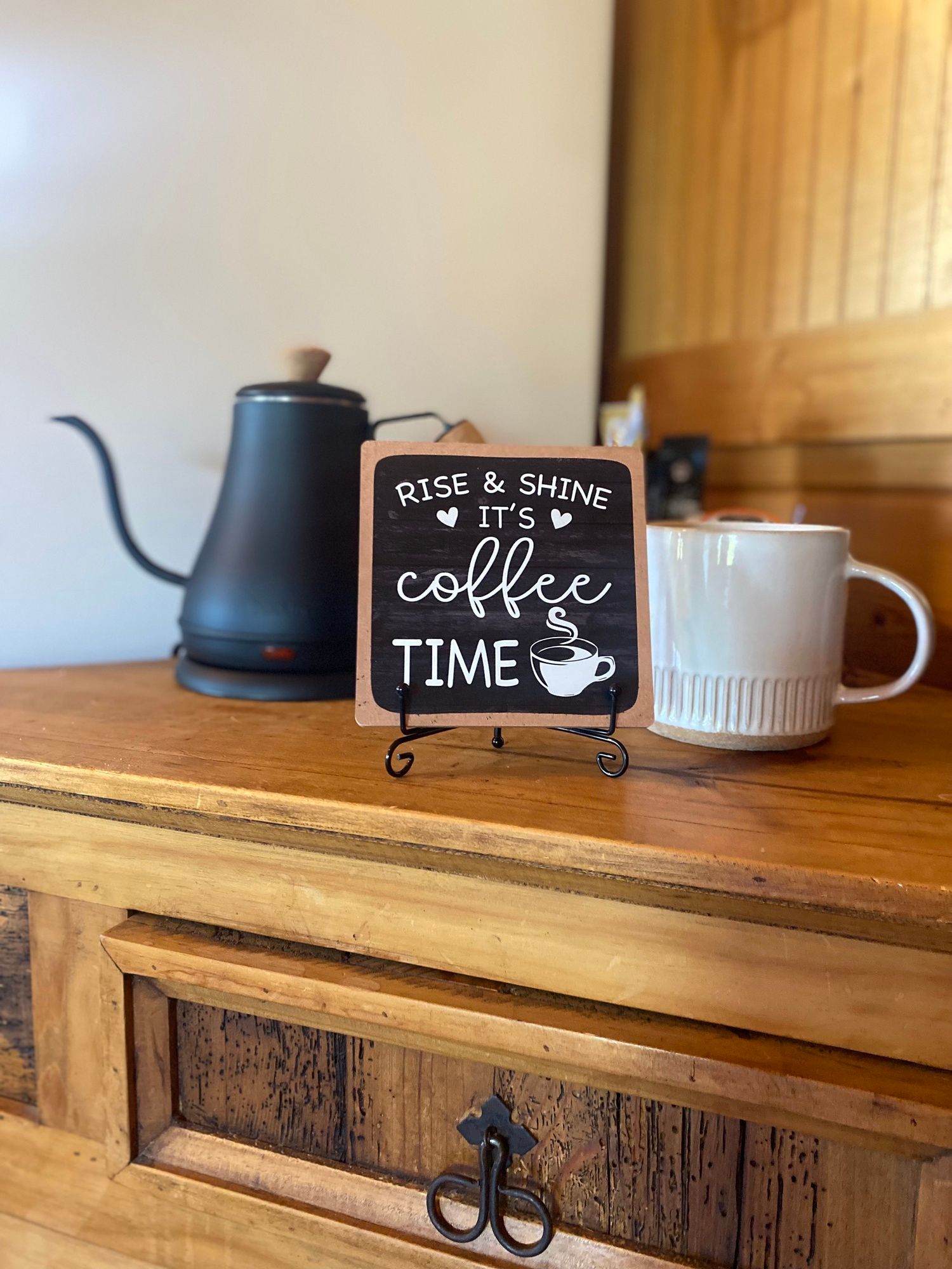 A cup of coffee is sitting on a wooden table next to a sign that says `` coffee time ''.