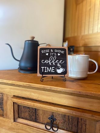 A cup of coffee is sitting on a wooden table next to a sign that says `` coffee time ''.