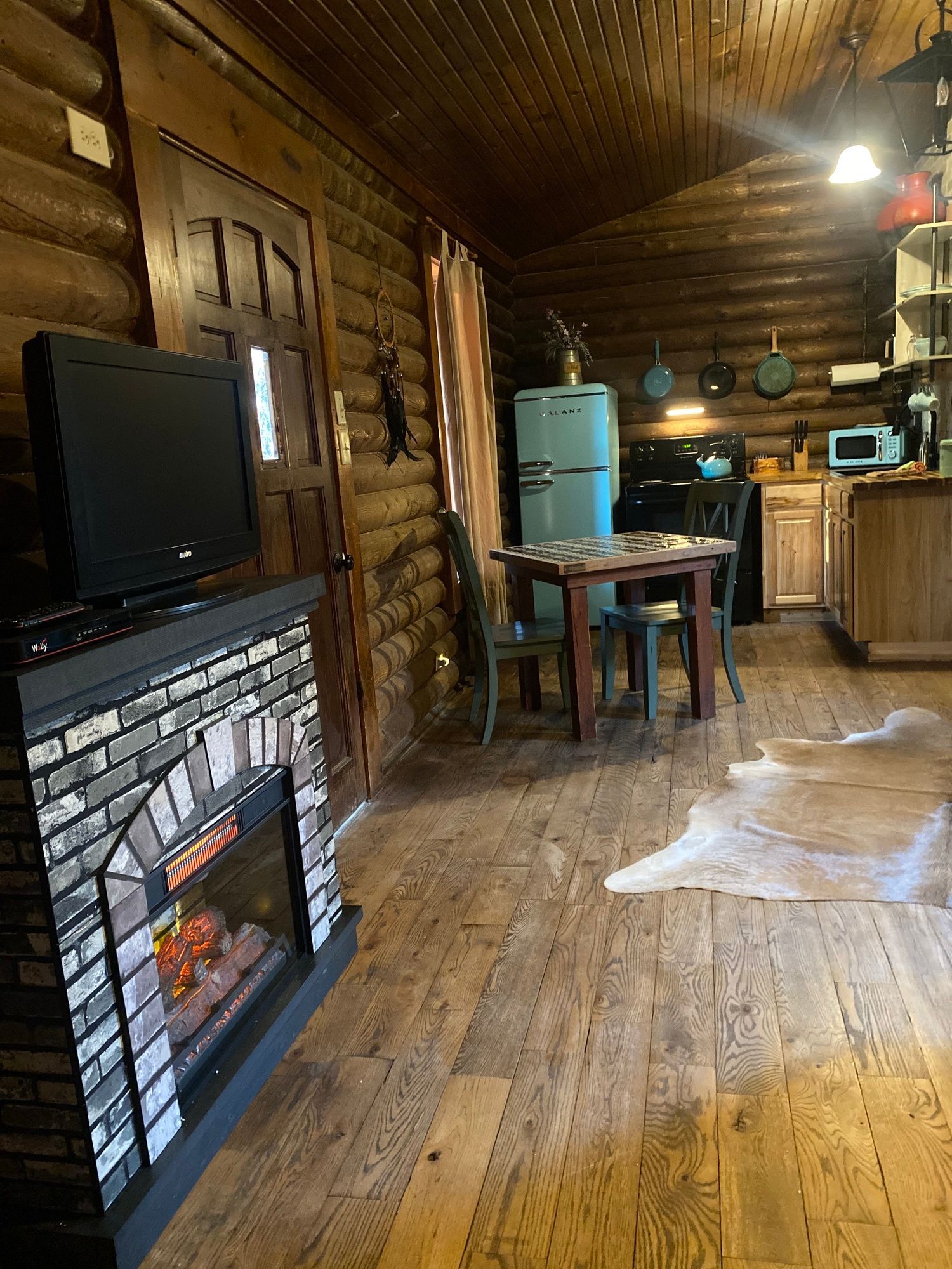 There is a fireplace in the middle of the room in a log cabin.