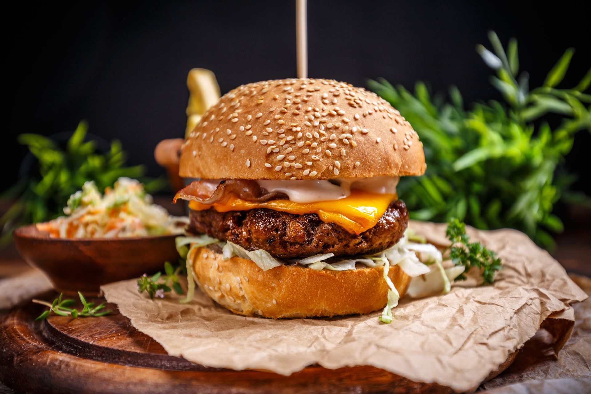 A hamburger is sitting on a wooden cutting board.