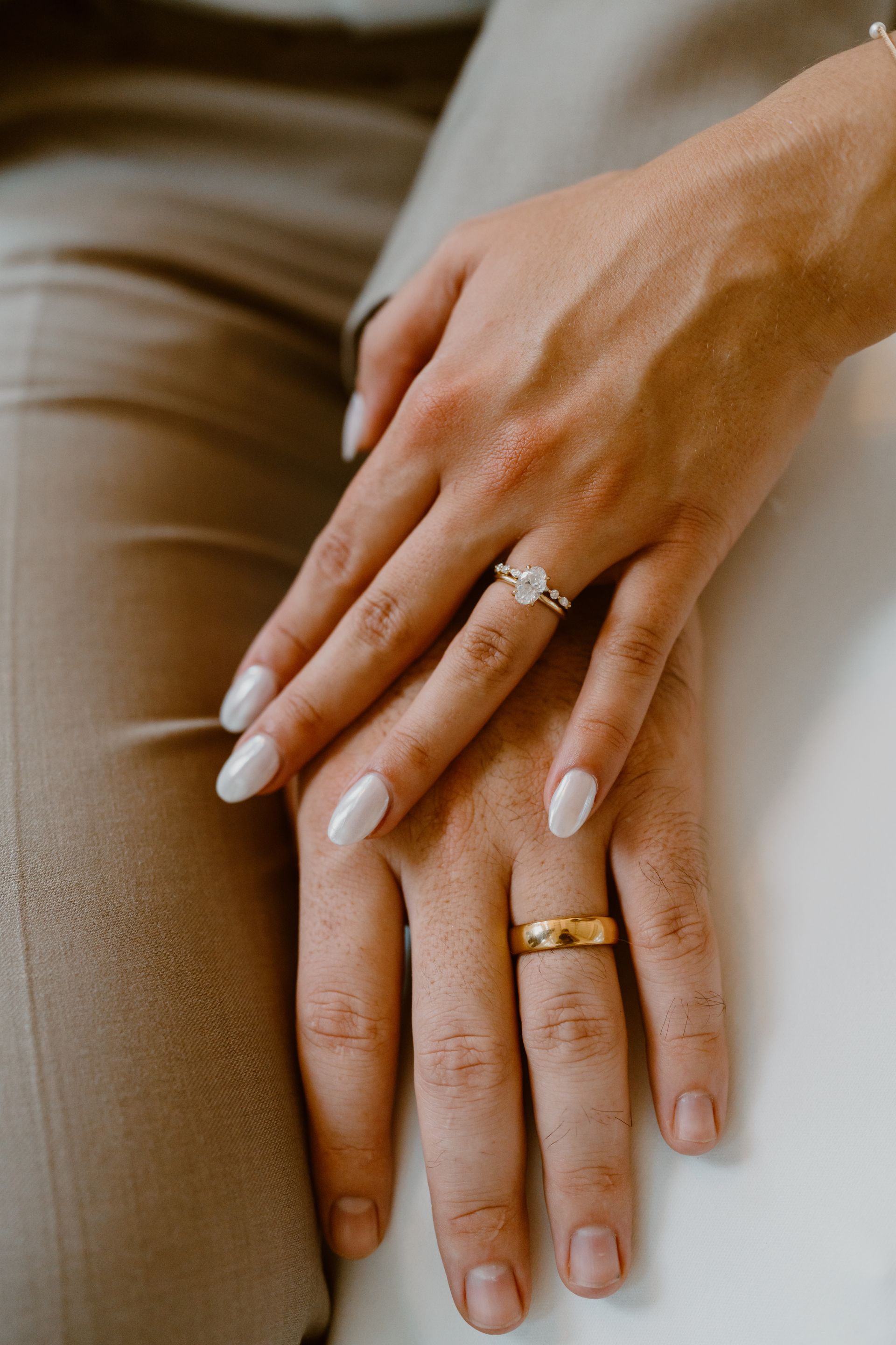 A close up of a bride and groom 's hands with wedding rings.