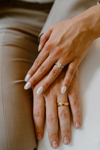 A close up of a bride and groom 's hands with wedding rings.