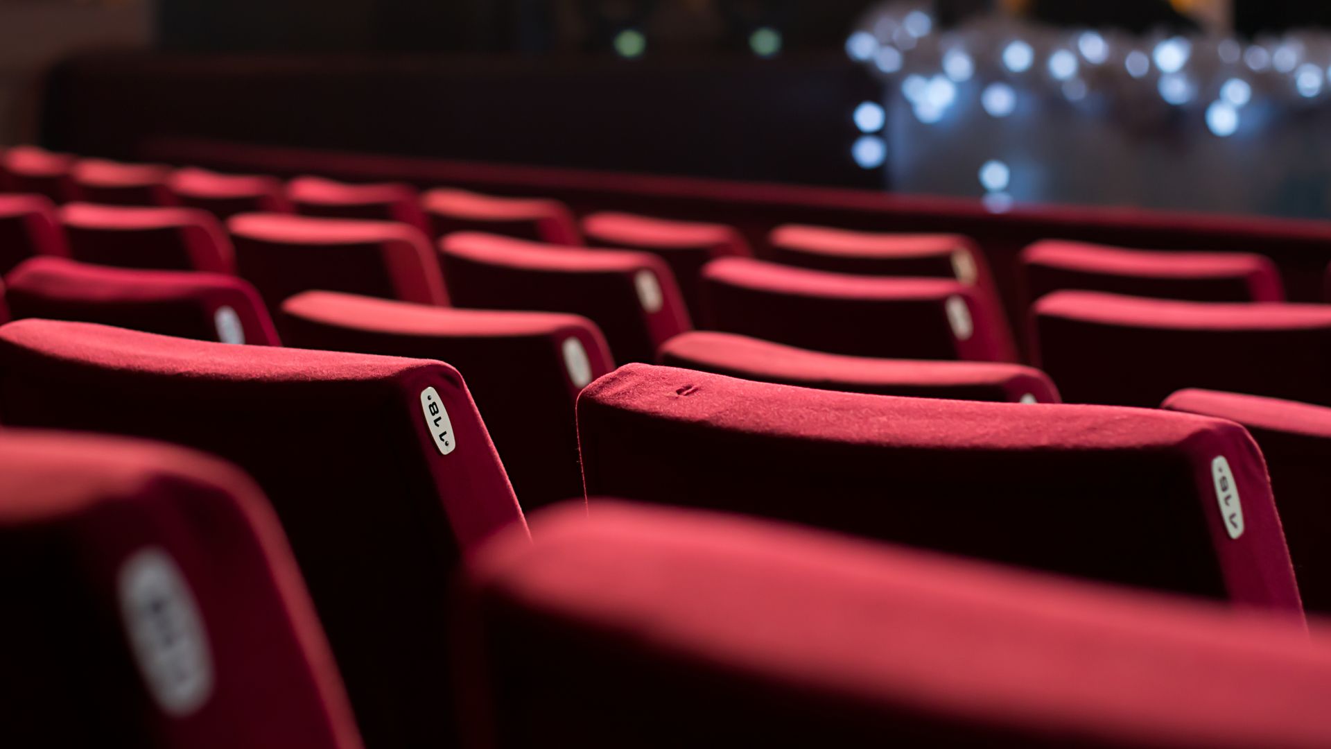 Rows of red seats in an auditorium with a stage in the background.