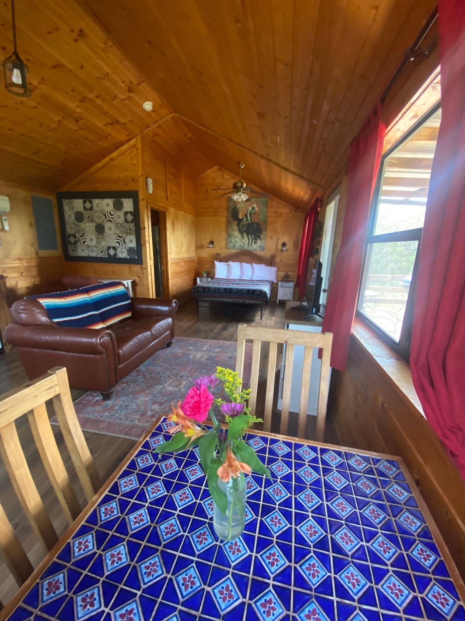 A living room with a table and chairs and a vase of flowers on it.