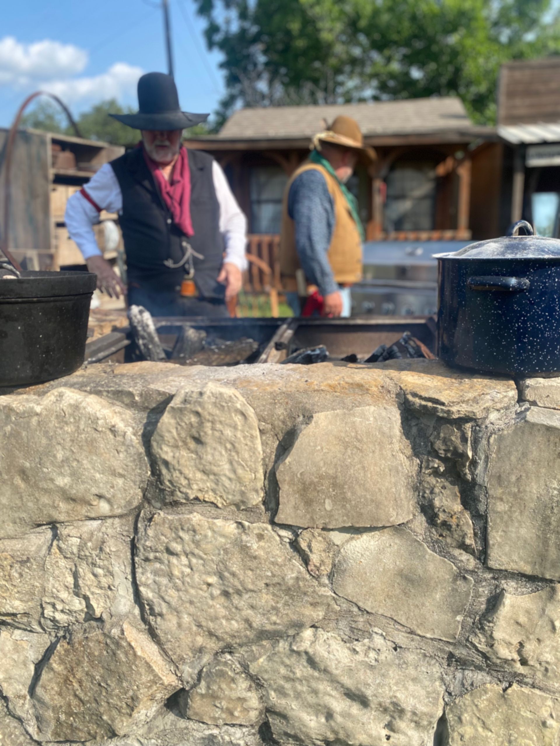 A man in a cowboy hat is cooking on a grill