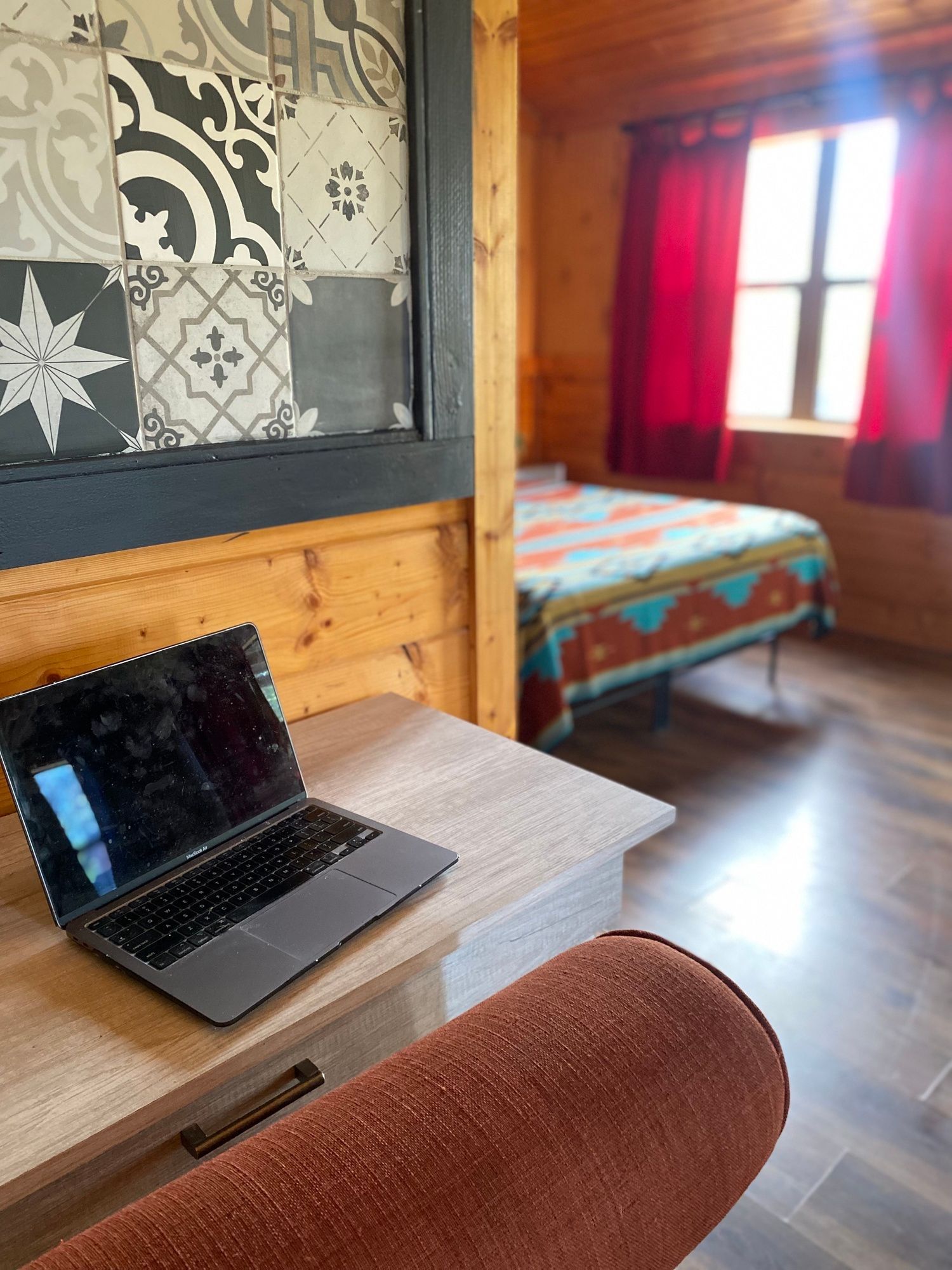 A laptop is sitting on a desk in a room next to a bed.