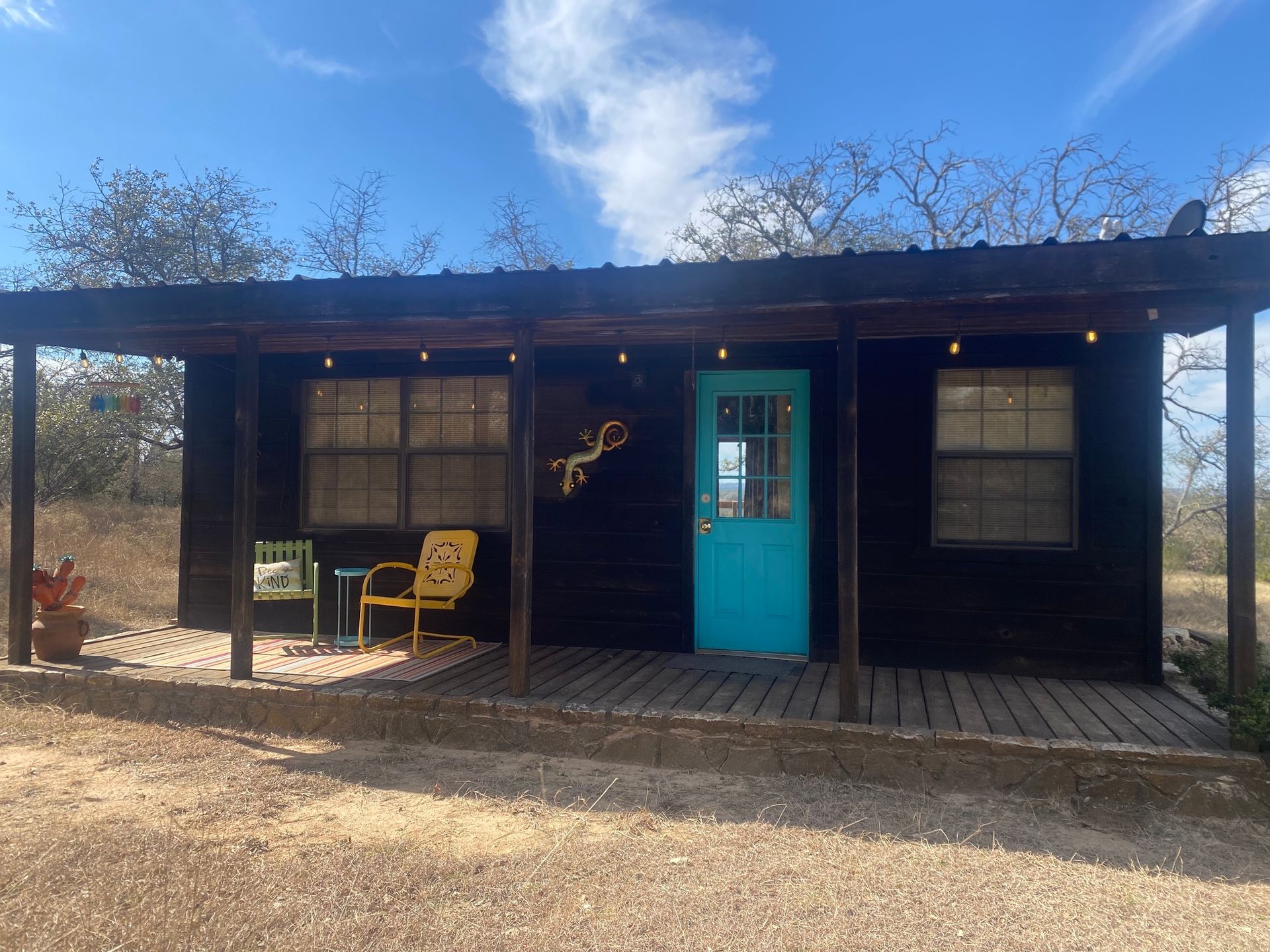 A small black house with a blue door and a porch.