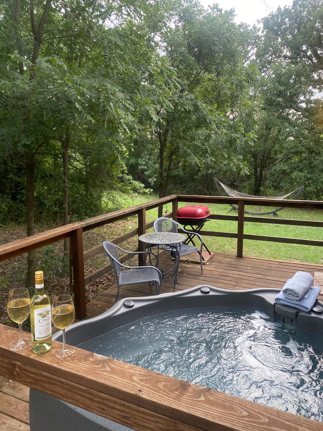 A hot tub is sitting on a wooden deck next to a table and chairs.