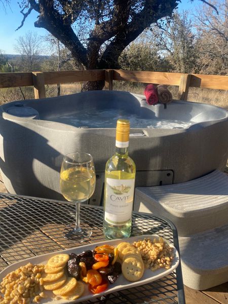 A bottle of wine sits on a table next to a hot tub
