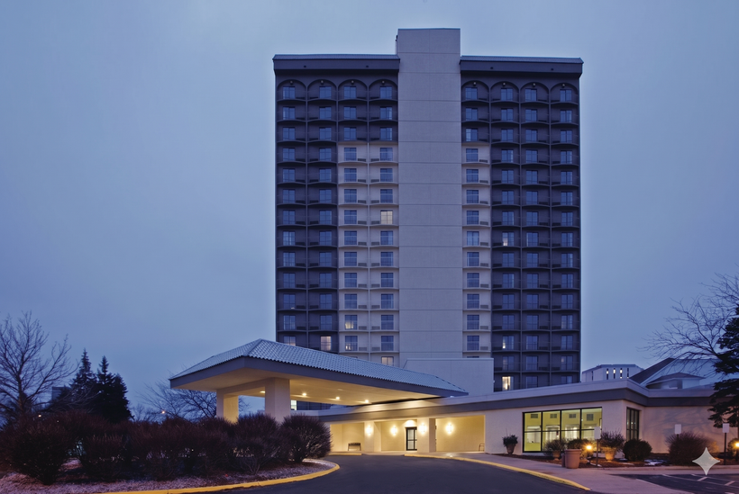 Tall hotel tower behind a lit entrance canopy at dusk