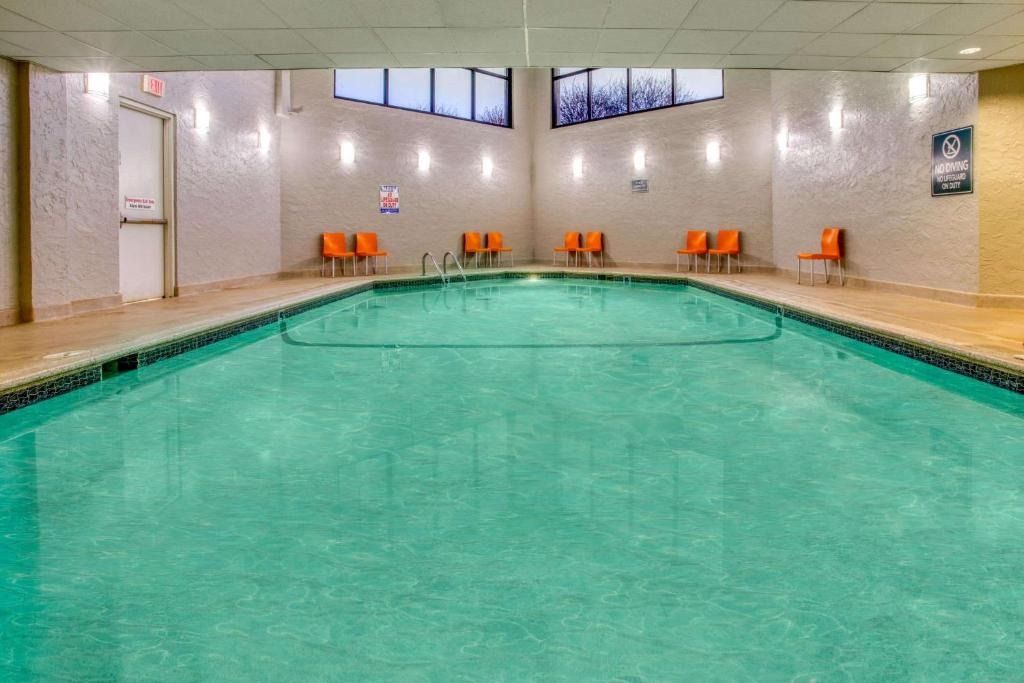 Indoor pool with turquoise water, orange chairs, and tiled walls under skylights