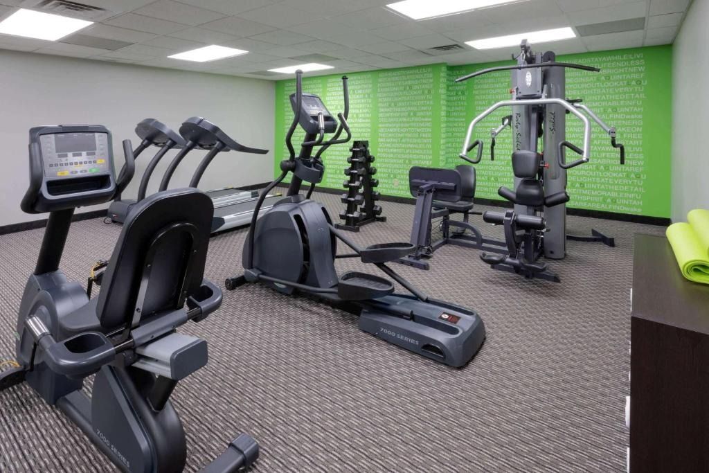 Empty gym with treadmills, weight machines, and a bright green accent wall
