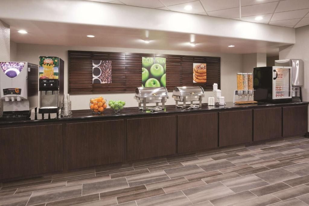 Empty hotel buffet setup with coffee dispensers and food trays on a long counter