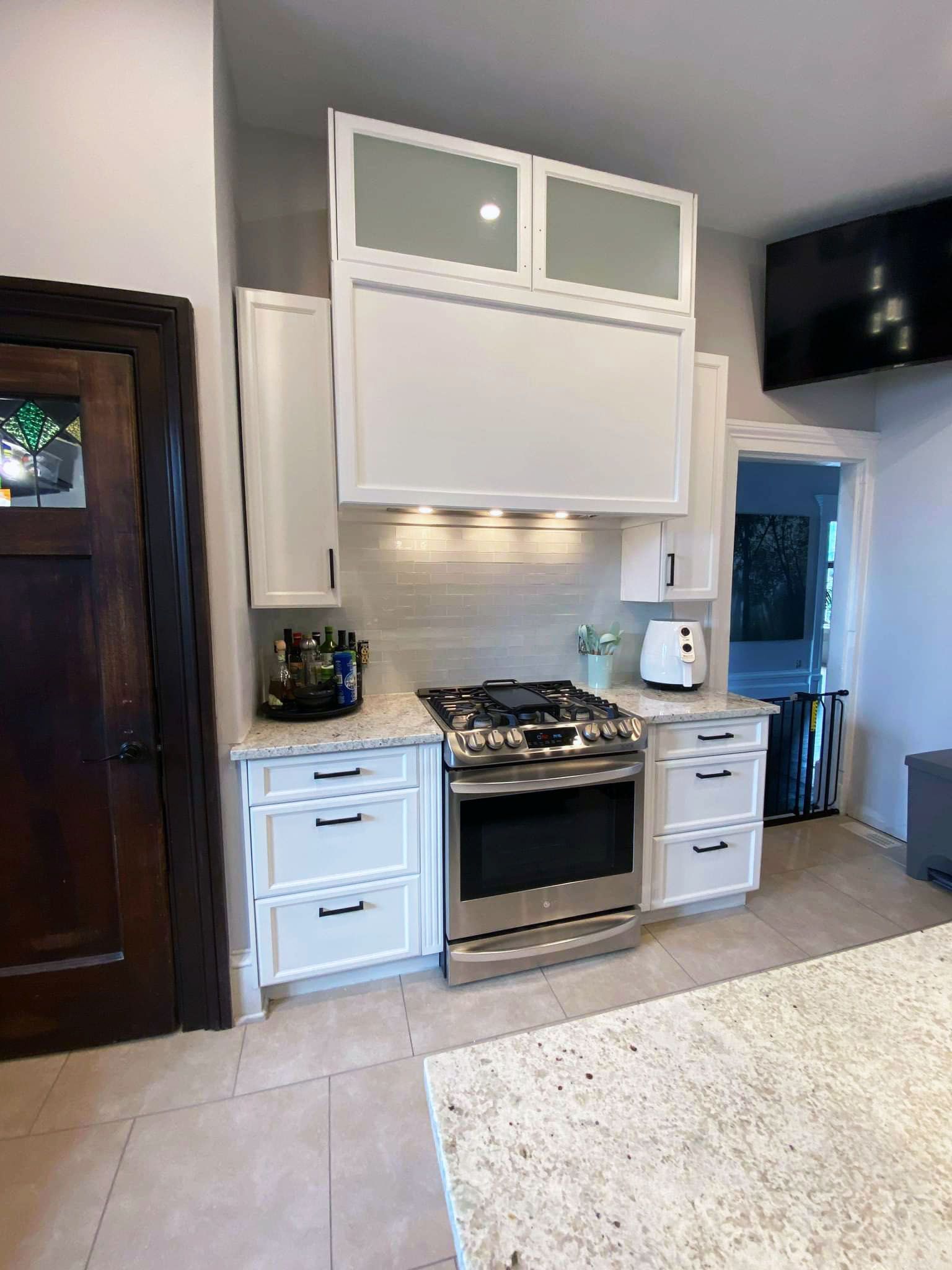 Une cuisine avec des armoires blanches, des appareils électroménagers en acier inoxydable, des comptoirs en granit et une cuisinière.