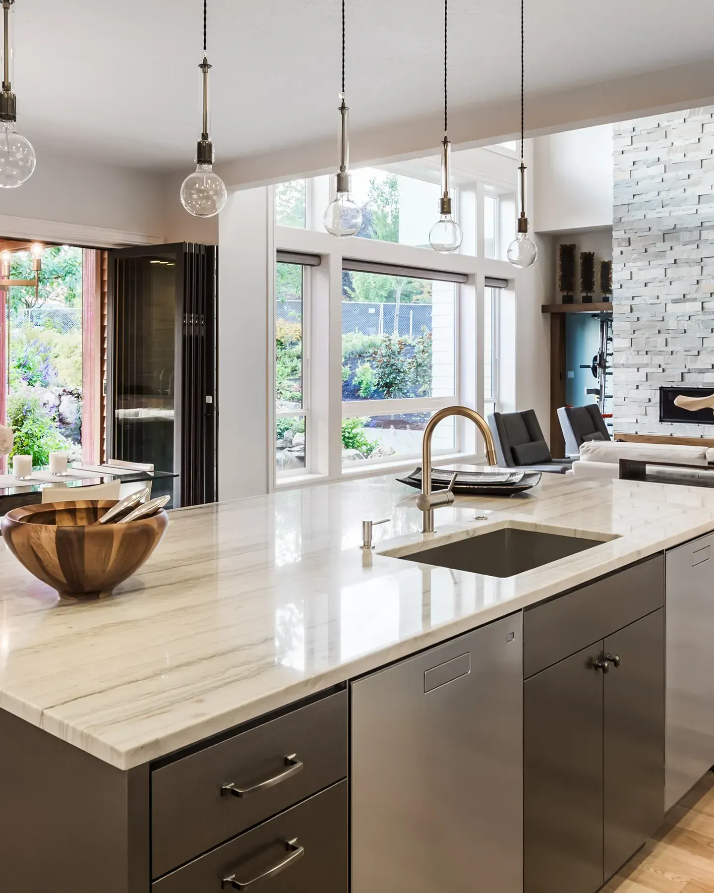 Une cuisine avec un grand îlot, un évier, des armoires et des électroménagers en acier inoxydable.