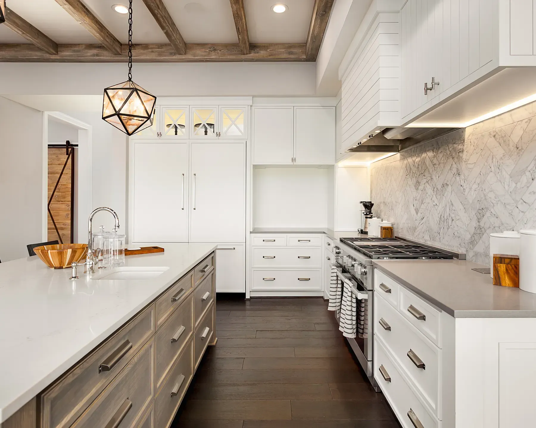 Une cuisine avec des armoires blanches, une cuisinière, un évier et un réfrigérateur.