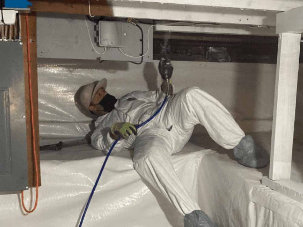 Person in protective suit working in crawlspace.