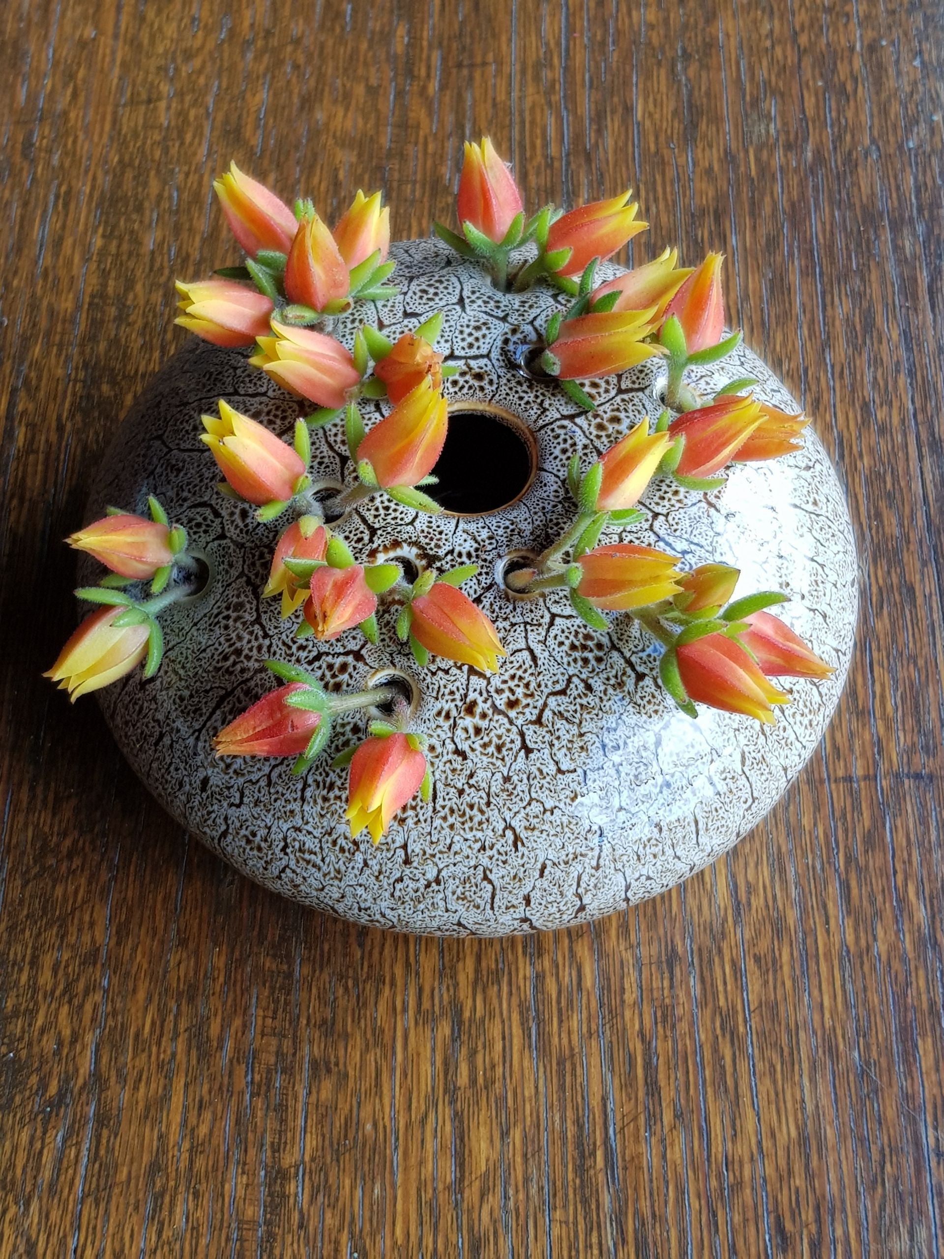 A PoseyPot filled with flowers on a wooden table