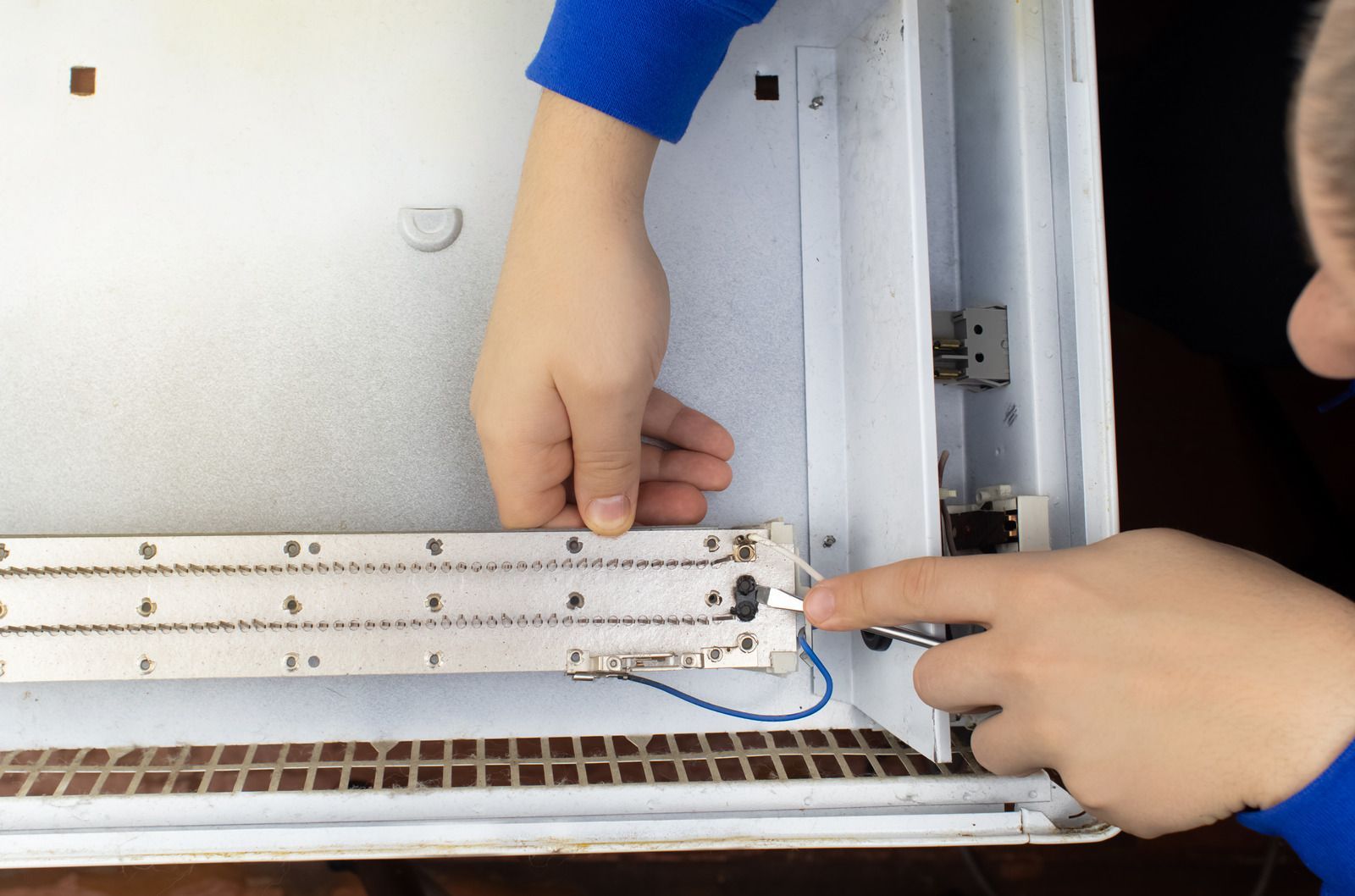 Person installing a light fixture inside a white cabinet, pointing with a finger.