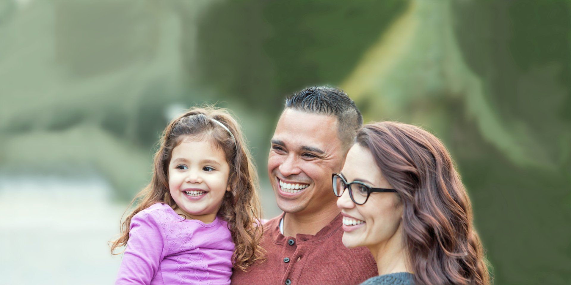 A man and woman are holding a little girl and smiling.