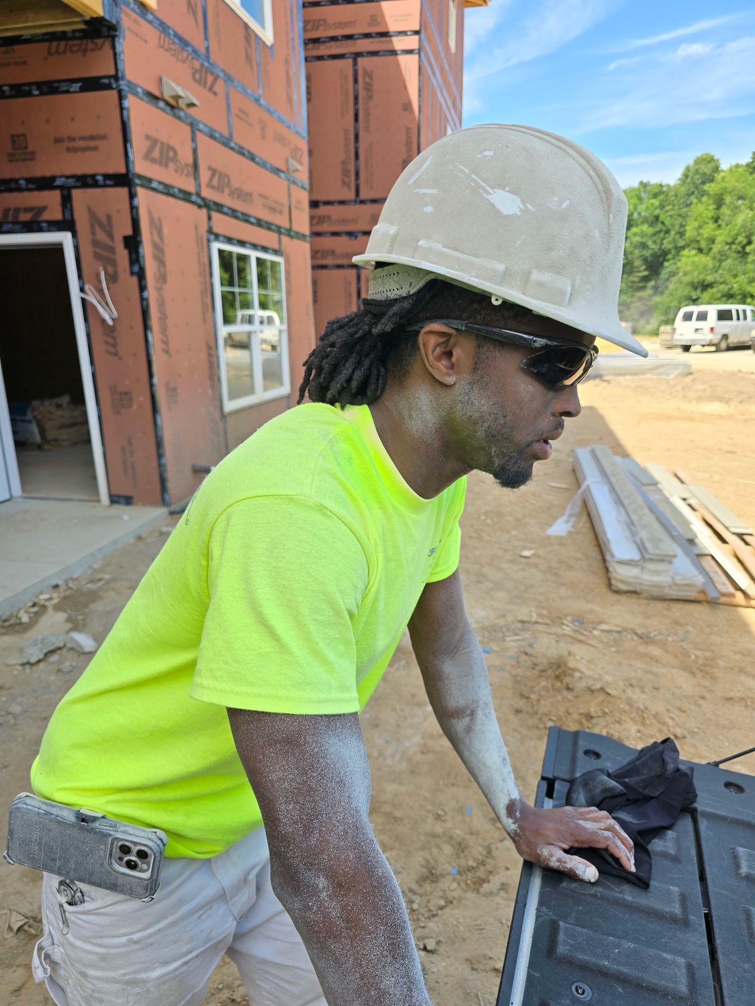 Construction worker in neon shirt and hard hat working on a building site.