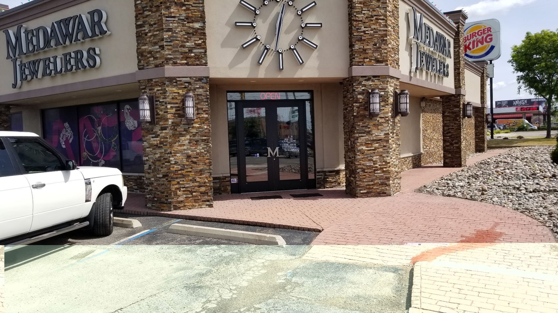 Medawar Jewelers storefront with a Burger King sign visible. White SUV parked in front.