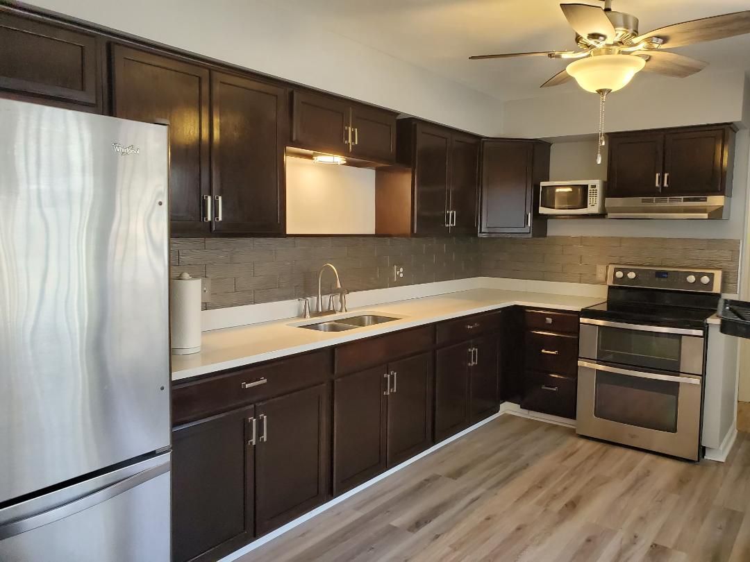 Kitchen with dark brown cabinets, stainless steel appliances, and light-colored countertops.
