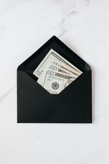A black envelope with several dollar bills in it for tip.