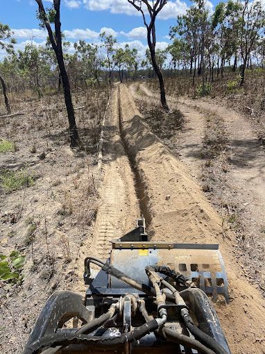A Yellow and Black Construction Vehicle is Parked in a Dirt Field — RCJJ Mini Loaders In Mareeba, QLD