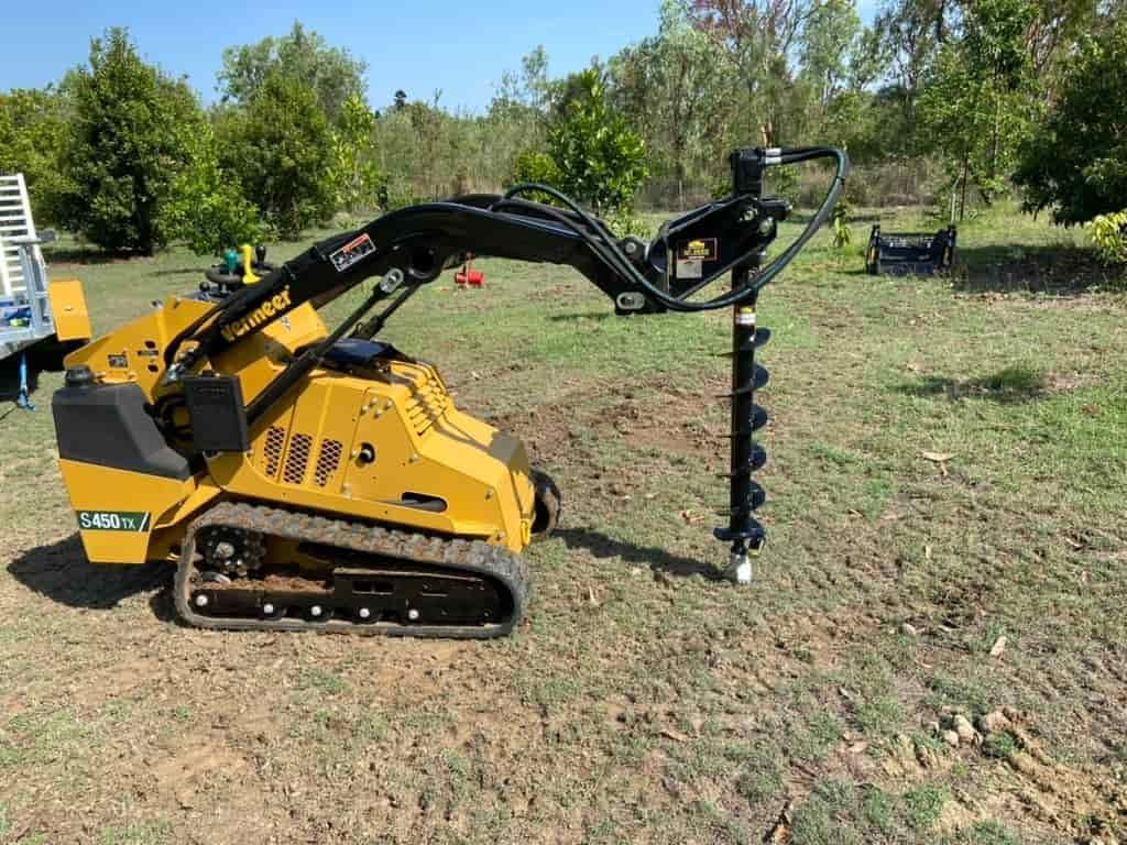 A Yellow Tractor With a Drill Attached to It is Sitting in a Field — RCJJ Mini Loaders In Mareeba, QLD