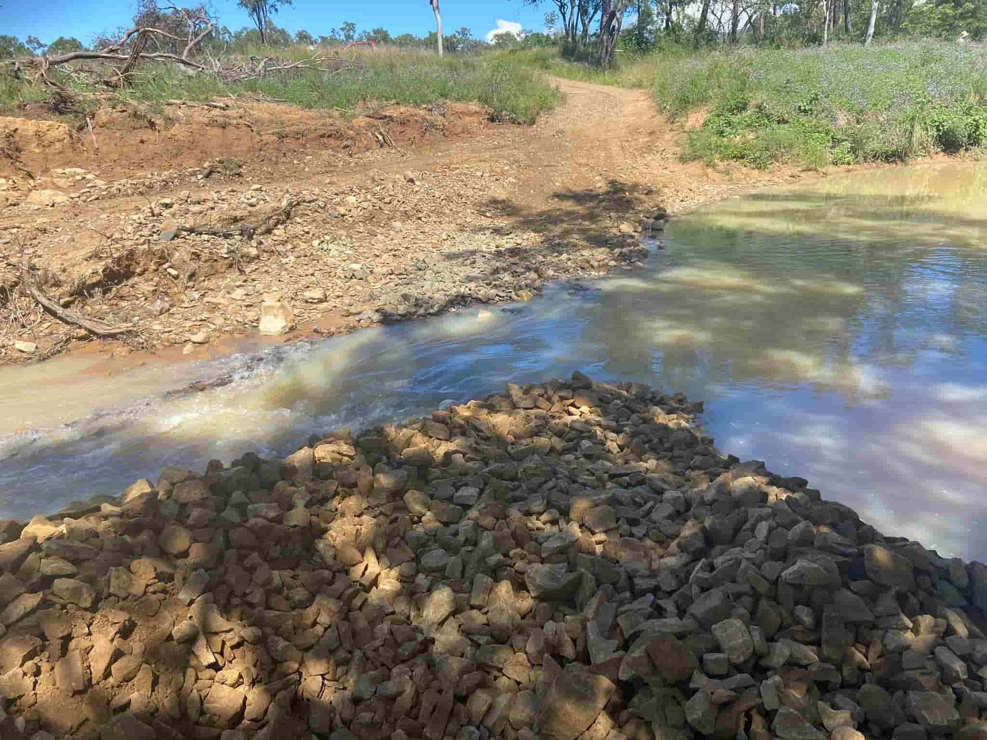 A Pile of Rocks is Sitting Next to a River — RCJJ Mini Loaders In Mareeba, QLD
